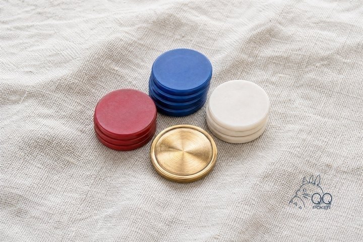 一枚黄铜庄家按钮与三叠高低不同的素面筹码围成弧形，正俯拍